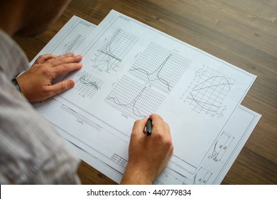 Man analyst working with documents, drawings, diagrams, graphics. With vignette.