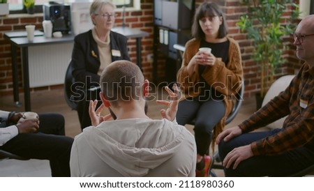 Man with anger management issues talking to people and counselor at aa group meeting to cure mental health problems. Angry adult discussing about alcohol addiction and depression.