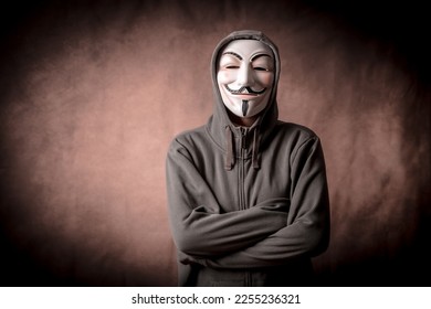 Man with anonymous mask with sweatshirt, looking at camera, studio shot
