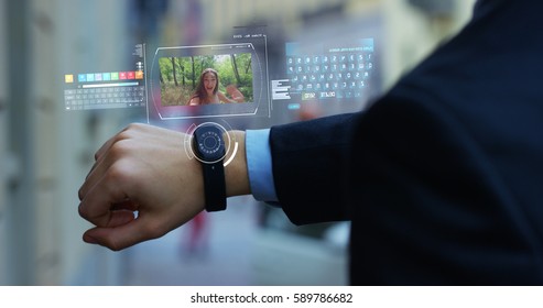 A Man Answers The Wife Who Smiles And Waves From The Phone That Appears In Hologram Clock Futuristic And Technological. Concept: Network, Communication,family, Technology, Augmented Reality And Future