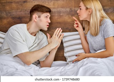 Man Apologizes To His Wife, Wife Chastises Her Husband For His Antics. Young Caucasian Married Couple Argue On Bed In The Morning