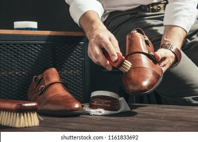 Man applies shoe polish with a small brush