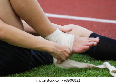 man applying compression bandage onto ankle injury of a football player, Sports injuries.
