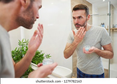 Man Applying Face Cream On His Face In Bathroom