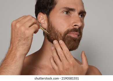 Man Applying Oil Onto Beard On Grey Background, Closeup