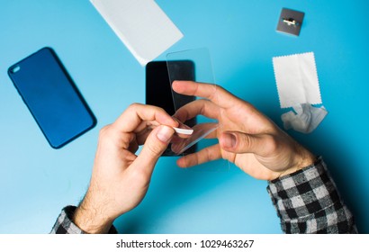 Man Applying Protective Tempered Glass To Smart Phone Screen