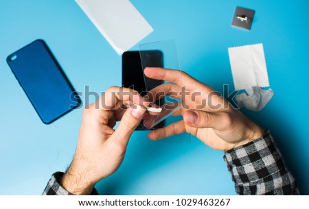 Man applying protective tempered glass to smart phone screen