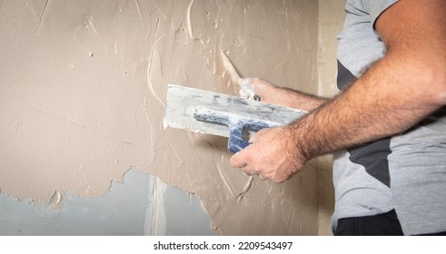 Man Is Applying Putty On A Wall. Renovating House 