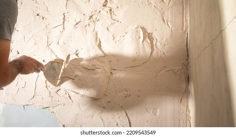 Man Is Applying Putty On A Wall. Renovating House 