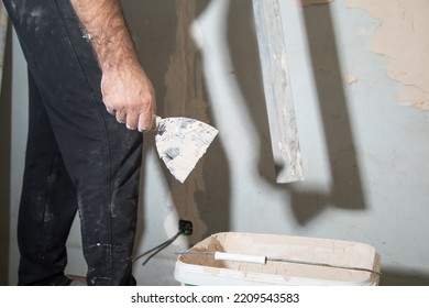 Man Is Applying Putty On A Wall. Renovating House 