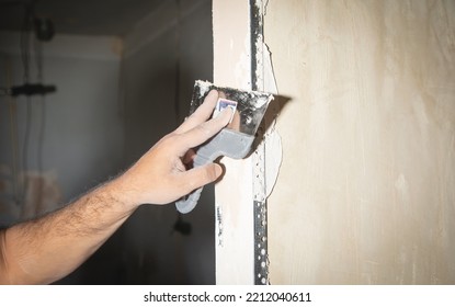 Man Is Applying Putty On A Wall. Renovating House 