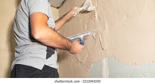 Man Is Applying Putty On A Wall. Renovating House 