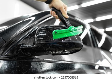 Man applying sticking protective film on a car mirror at the vehicle service station. Detailing studio. - Shutterstock ID 2257008565