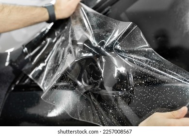Man applying sticking protective film on a car mirror at the vehicle service station. Detailing studio. - Shutterstock ID 2257008567