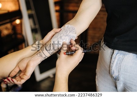 Man applying a tattoo stencil on woman hand. Tattoo artist begin work