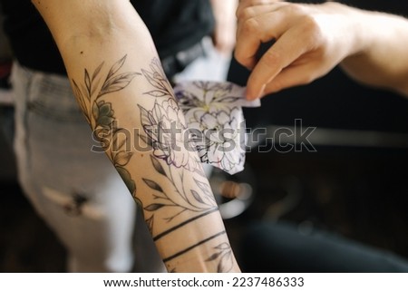 Man applying a tattoo stencil on woman hand. Tattoo artist begin work