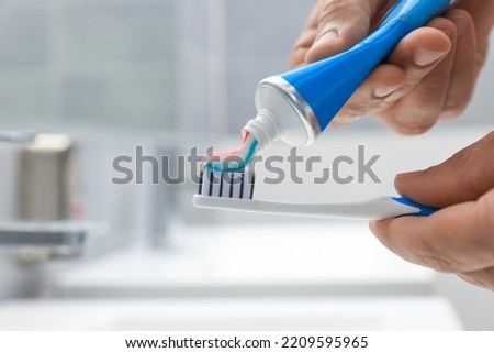 Man applying toothpaste on brush in bathroom, closeup. Space for text