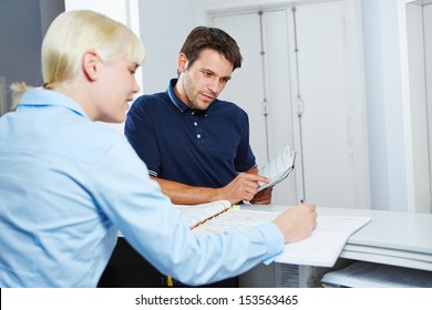 Man With Appointment Book Scheduling An Appointment At Reception Of Dentist