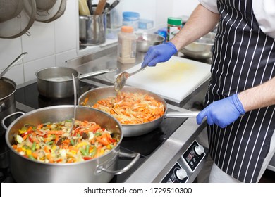 Man In Apron And Gloves Cooking Fresh Vegetables For Healthy Food Take Away Delivery, Quarantine