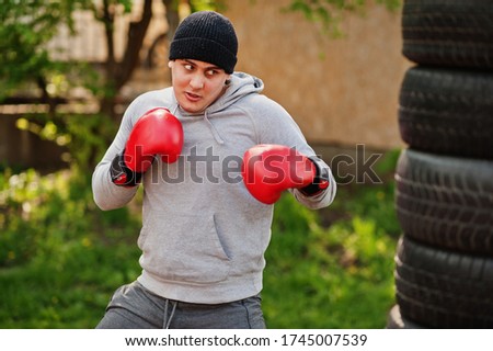 Man arabian boxer in hat training for a hard fight outdoor gym.
