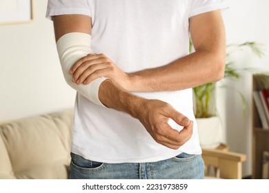 Man with arm wrapped in medical bandage indoors, closeup