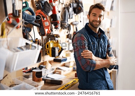 Man, arms crossed with tools and portrait in workshop, drill for diy repair and maintenance for job or skill. Artisan, handyman or carpenter with smile and confident with equipment for repairs