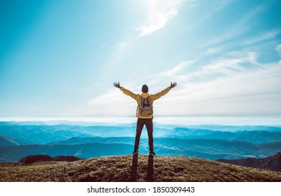 Man with arms up on the top of the mountain - Hiker on the cliff raising hands to the sky. - Powered by Shutterstock