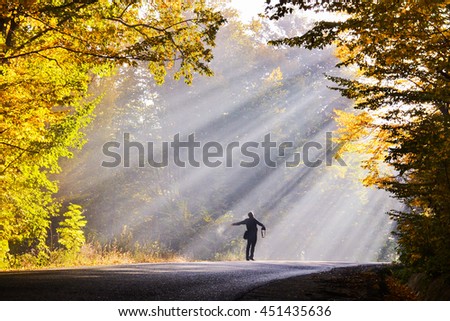 Man with arms open towards morning sunlight rays
