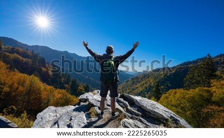 Man with arms raised relaxing on autumn hiking trip. Man on top of the mountain enjoying beautiful fall scenery. Blue Ridge Mountains, near Asheville, North Carolina, USA