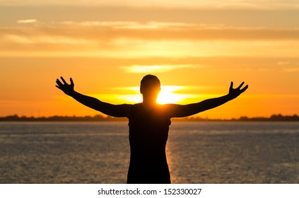 Man With Arms Wide Open On The Beach At Sunrise