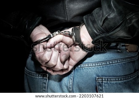 A man is arrested and handcuffed before being transported to jail.