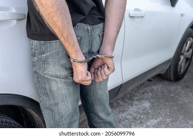 MAN ARRESTED AND HANDCUFFED BY THE POLICE ON THE STREET NEXT TO A CAR. REAR VIEW. - Powered by Shutterstock