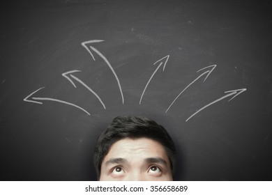 Man with arrows on the blackboard background. - Shutterstock ID 356658689