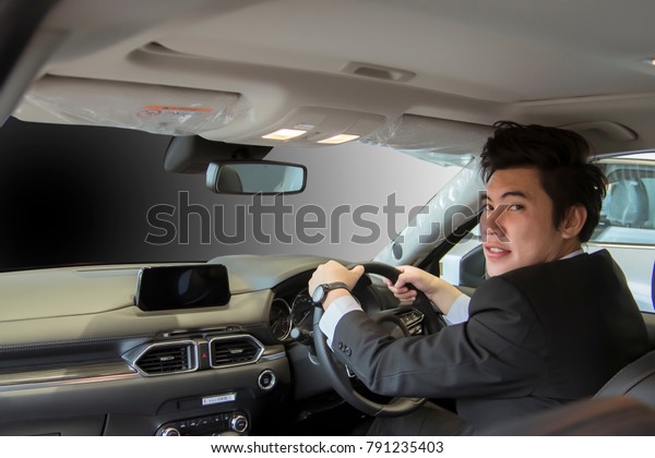 man asia driving\
car on blurry background in showroom. Using wallpaper for\
transport, automotive and car\
image.