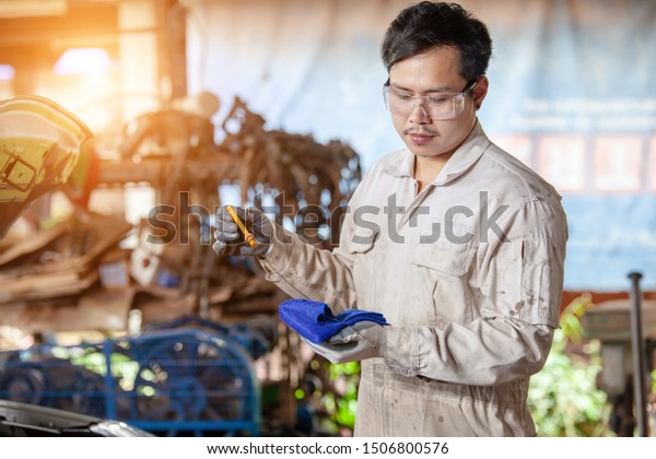 man\
asia Mechanic checking oil level in a car\
workshop