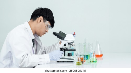 Man asian student education learning scientist wearing doctor gown in lab looking hand at chemist. caused by mixing reagents in scientific research laboratories with test tubes and microscope on table - Powered by Shutterstock