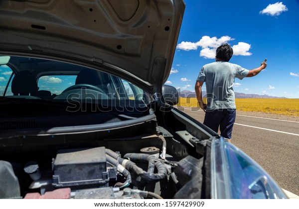 Man\
asking for a ride in a highway with a broken\
car