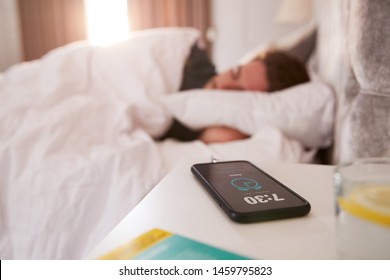 Man Asleep In Bed With Mobile Phone On Bedside Table