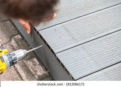 Man assembling composite deck using cordless screwdriver - Shutterstock ID 1813086172