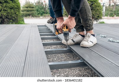 Man assembling composite deck using cordless screwdriver.