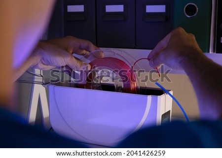 Man assembling filament of 3D printer. View from behind