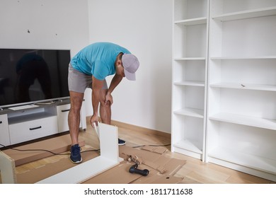 Mann, der Möbel in einer neuen Wohnung zusammenbaut, einzieht und fleißig arbeitet.