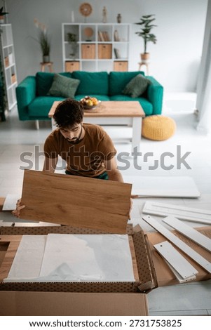 Man assembling and installing flat-pack furniture at home, creating diy projects in a modern living space