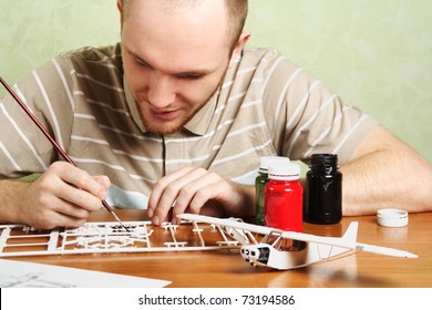 Man Assembling Plastic Airplane Model And Painting Pieces