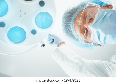 Man assistant surgeon in protective uniform places a surgical lamp for operation. Point of view shot - Powered by Shutterstock