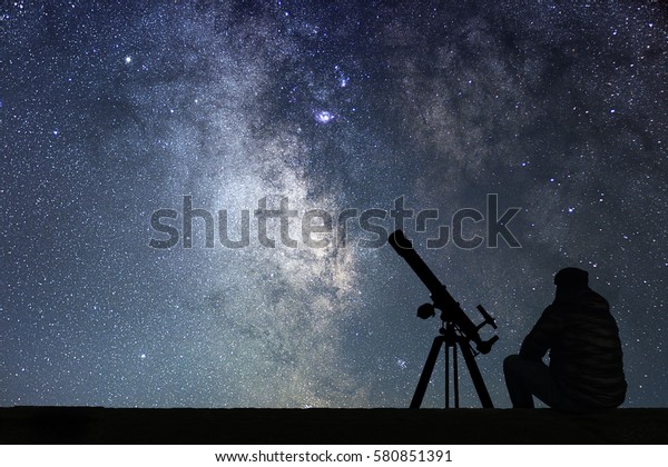 Man with\
astronomy  telescope looking at the stars. Man telescope and starry\
sky. Night sky. Milky way\
galaxy.