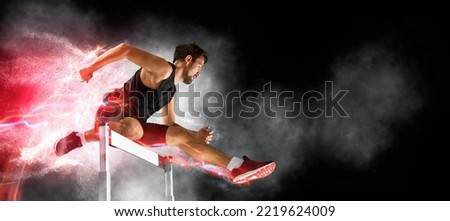 Man athlete at hurdle race, jumping over the last hurdle. Red neon background. Sport banner