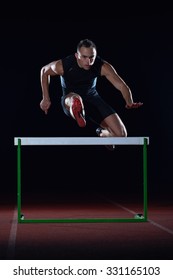 man athlete jumping over a hurdles on athletics race track