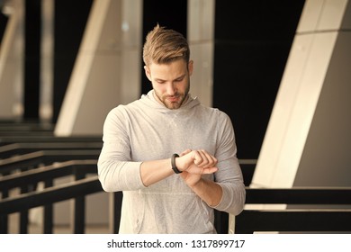 Man Athlete On Strict Face Checking Fitness Tracker, Urban Background. Athlete With Bristle With Fitness Tracker Or Pedometer. Sportsman Training With Pedometer Gadget. Sport Gadget Concept.