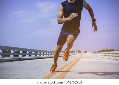 The man athlete runners jogging on the bridge. Fit young exercising healthy lifestyle outdoors during sunrise or sunset. - Powered by Shutterstock